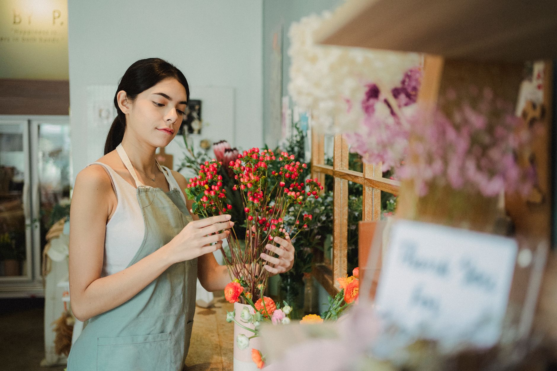 Florist arranging a composition of small red flowers in a shop