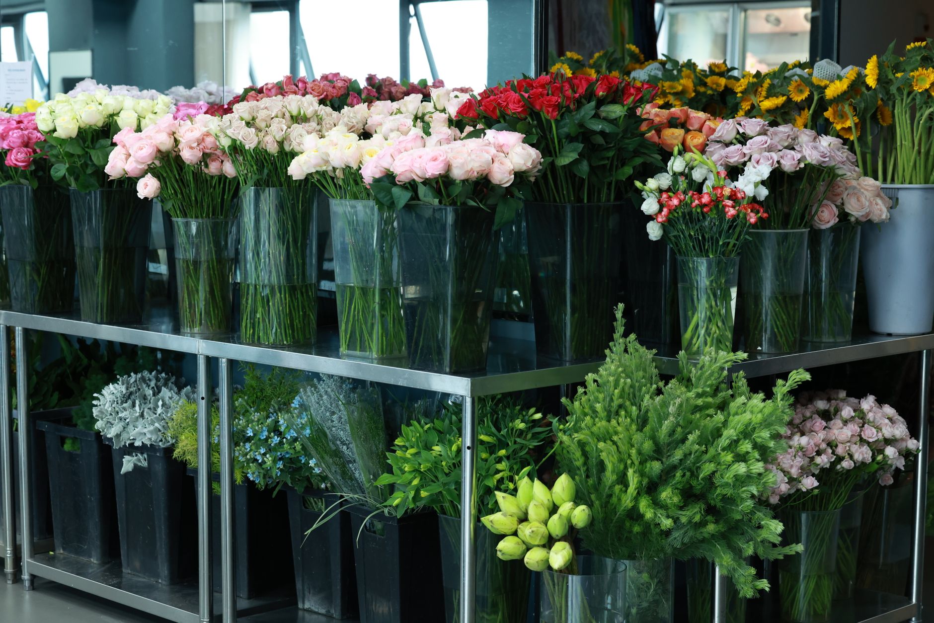 Fresh cut roses and sunflowers displayed in vases at a retail florist shop