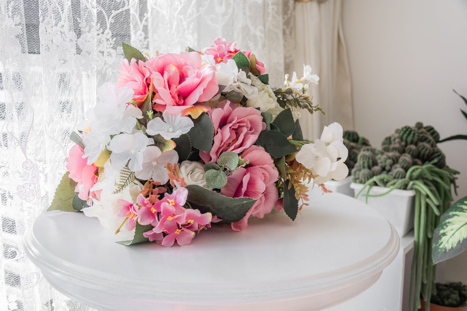 A bright artificial silk floral arrangement with pink and white flowers on an indoor table