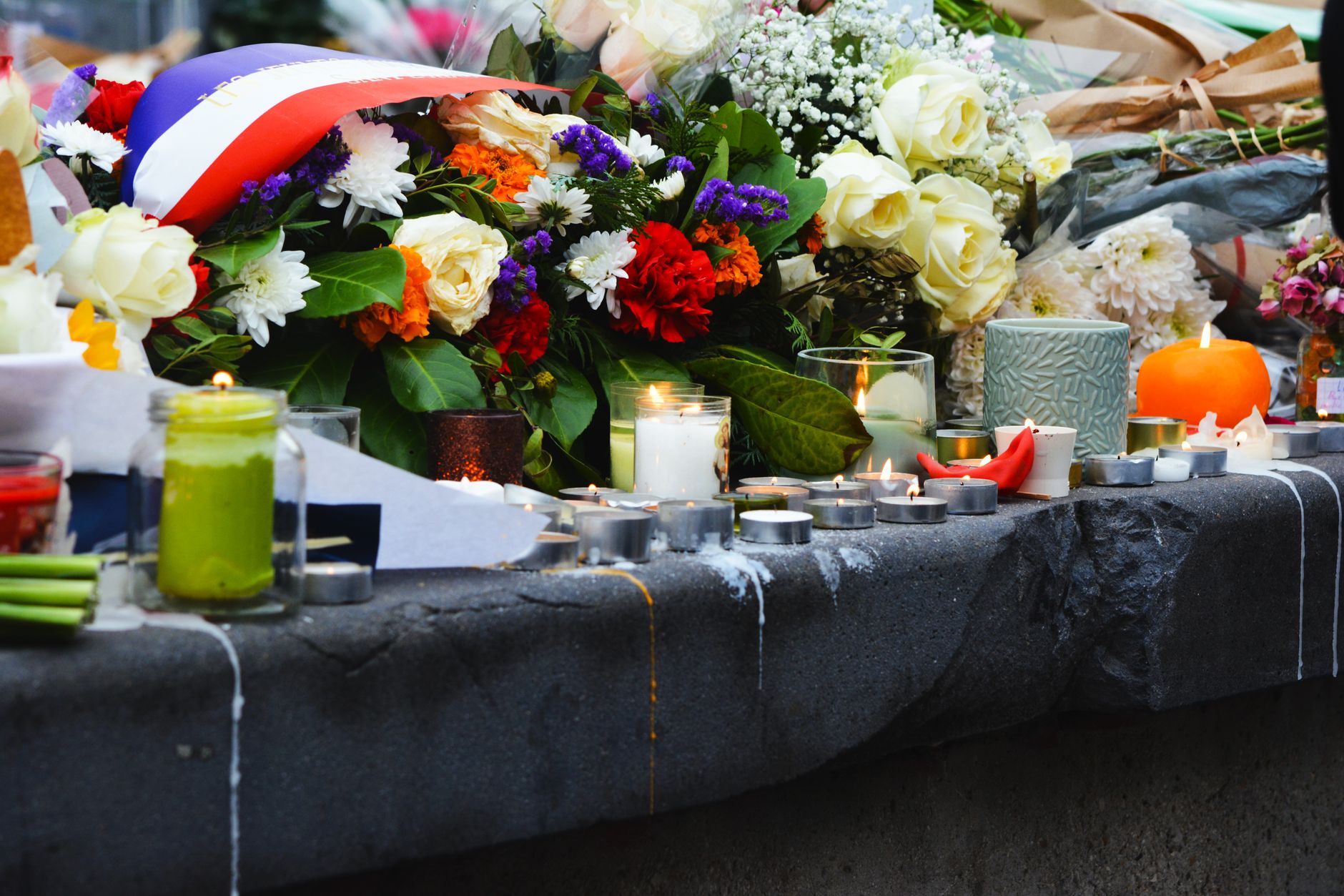 A quiet outdoor memorial with candles and floral tributes on a stone surface