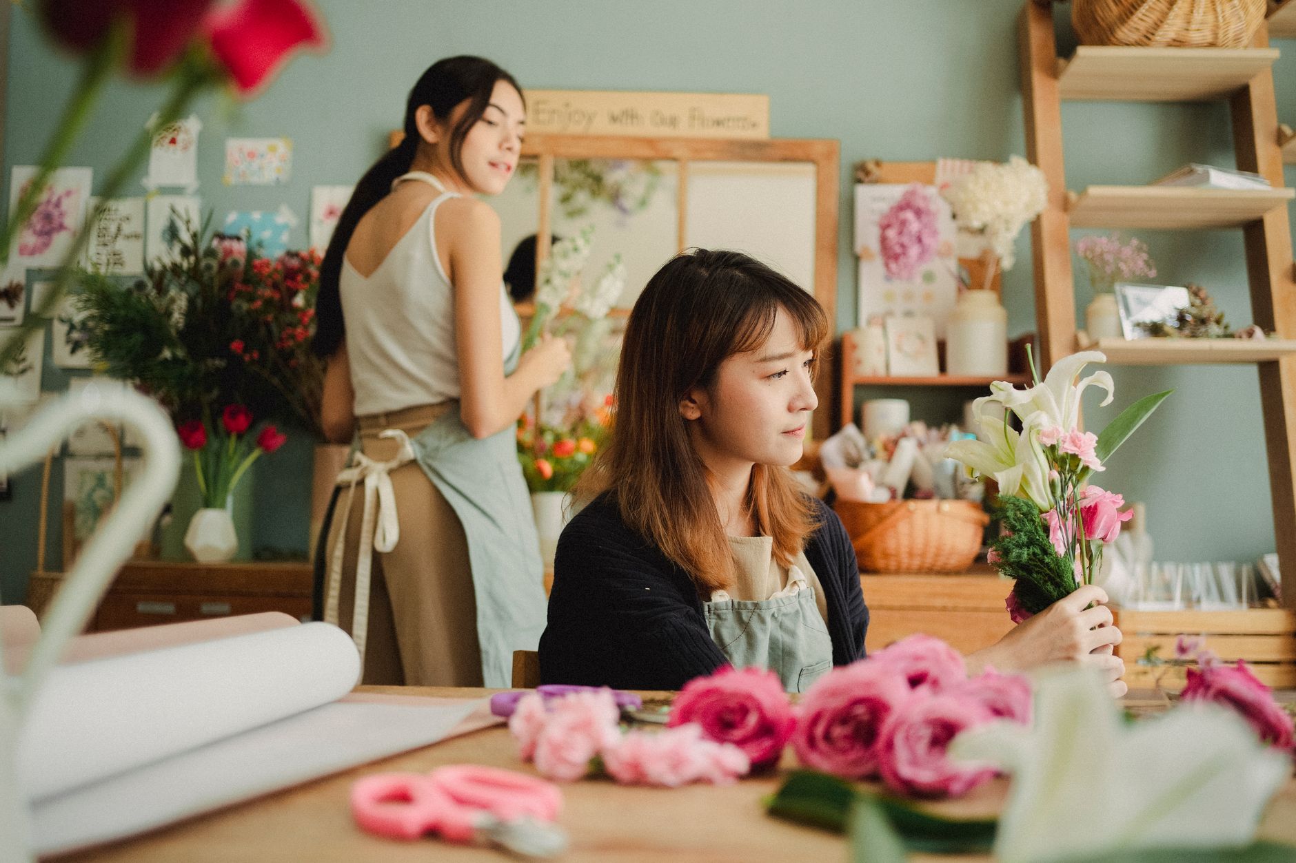 Florist arranging a bouquet with an assistant in a floral store